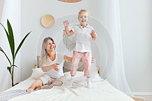 Happy mother and her daughter child girl playing and hugging in bedroom