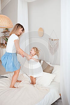 Happy mother and her daughter child girl playing and hugging in bedroom