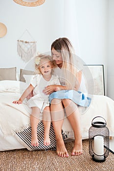 Happy mother and her daughter child girl playing and hugging in bedroom