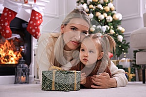 Happy mother and her daughter with Christmas gift in festively decorated room