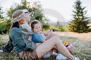 Happy mother and her daughter hugging together during family picnic in nature.