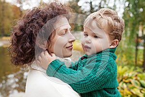 Happy mother and her little boy in the autumn park. Child playing with mother. Mother and son embracing