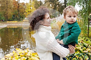 Happy mother and her little boy in the autumn park. Child playing with mother. Mother and son embracing