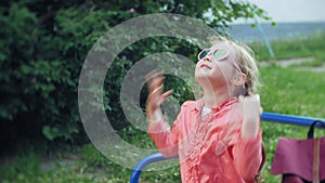 Happy Mother and her little Daughter playing together outdoor, blowing soap bubbles, having fun on backyard. Nature