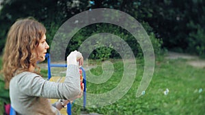 Happy Mother and her little Daughter playing together outdoor, blowing soap bubbles, having fun on backyard. Nature
