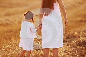 Happy mother with her little daughter spending time together outdoors on the field