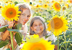 Happy mother and her little daughter in the sunflower field