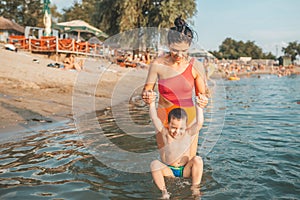 Happy mother and her little son playing and having fun in the water
