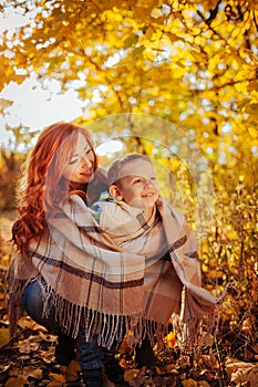 Happy mother and her little son walking and having fun in autumn forest.