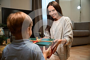 Happy mother and her son enjoying holiday by sharing gifts under the X-mas tree