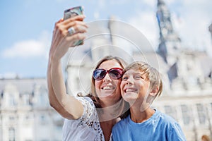 Happy mother and her son making selfie near Hotel de Ville in Paris. Tourists enjoying their vacation in France.