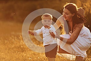 Happy mother with her son spending free time on the field at sunny day time of summer