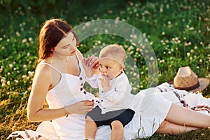 Happy mother with her son spending free time on the field at sunny day time of summer