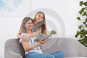 Happy mother and her teenage daughter with book