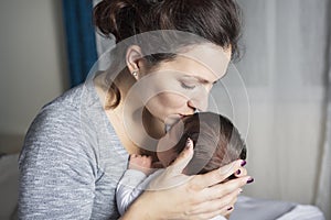 Happy mother holding adorable child baby on the living room