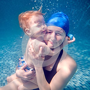 Happy mother holding baby in arms underwater.