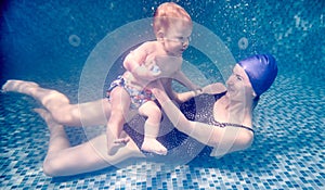 Happy mother holding cute son underwater.