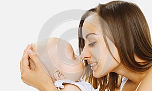 Happy mother holding on hands and kissing her little sleeping baby on a white background
