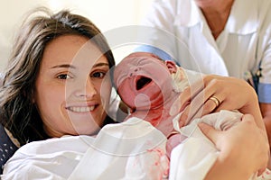 Happy mother holding her baby, seconds after she gave a birth, n