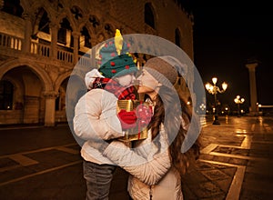 Happy mother hugging child with Christmas gift box in Venice