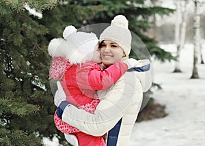 Happy mother hugging child near christmas tree in winter day
