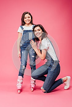 Happy mother hugging daughter in roller blades and looking at camera