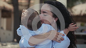 Happy Mother Hugging Her Child on the Coast. Cute Kid Kisses His Mom and Gently Hugs. Concept Mom With a Child Outdoors