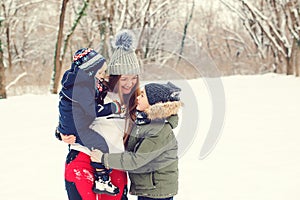 Happy mother hugging her cute sons, smiling and laughing. Winter fashion. Christmas and winter holidays. Happy kids with mom on a