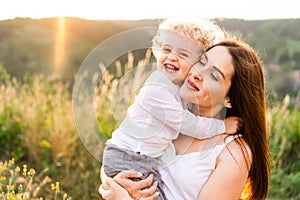 Happy mother hugging her son at sunset.