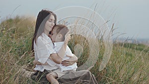 Happy mother hugging and kissing son while resting on hill