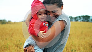 Happy mother hugging smiling child in the field with wheat.