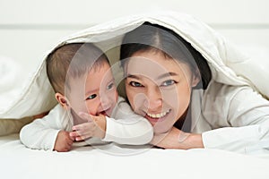 happy mother and infant baby lying prone in blanket on bed