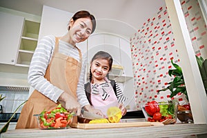 Happy Mother and kid preparing healthy food and having fun in kitchen at home