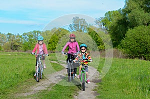 Happy mother and kids on bikes cycling outdoors