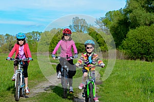 Happy mother and kids on bikes cycling outdoors