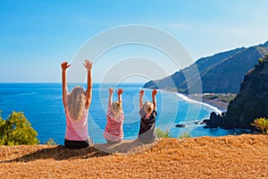 Happy mother, kids on hill with sea cliffs scenic view