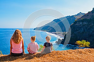 Happy mother, kids on hill with sea cliffs scenic view