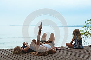 Happy mother, kids relaxing, talking on veranda with beautiful view