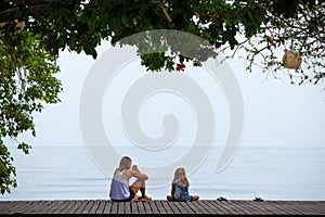 Happy mother, kids relaxing, talking on veranda with beautiful view