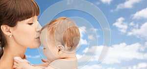 Happy mother kissing baby boy over sky background