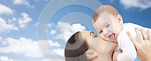 Happy mother kissing her baby over blue sky