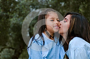 Happy mother kissing her daughter enjoying a winter afternoon