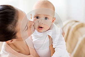 Happy mother kissing little baby boy at home