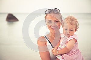 Happy mother with little child at beach during vacation. Mom holding in hands her child.