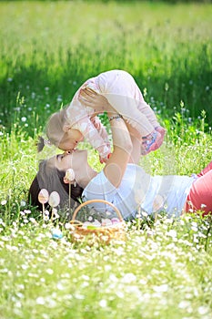 Happy mother and little child hugging kissing in spring park on nature. Mom throws her beloved healthy daughter up in