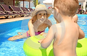 Happy mother with little child in swimming pool