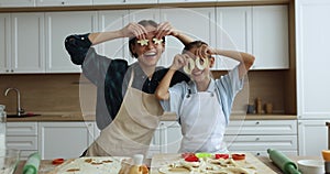 Happy mother little daughter in aprons having fun in kitchen