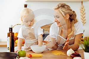 Happy mother and little daughter cooking in kitchen. Spending time all together, family fun concept