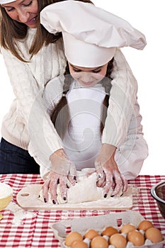 Happy mother with little daughter joyful cooking