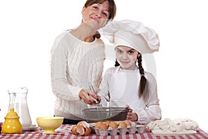 Happy mother with little daughter joyful cooking